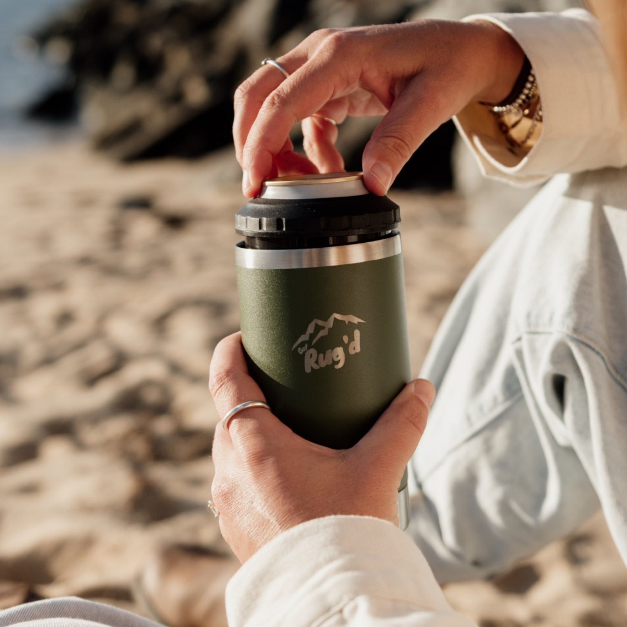 Person holding StubCup Green Stubby Cooler Coffee Cup by Get Rug'd on a sandy beach