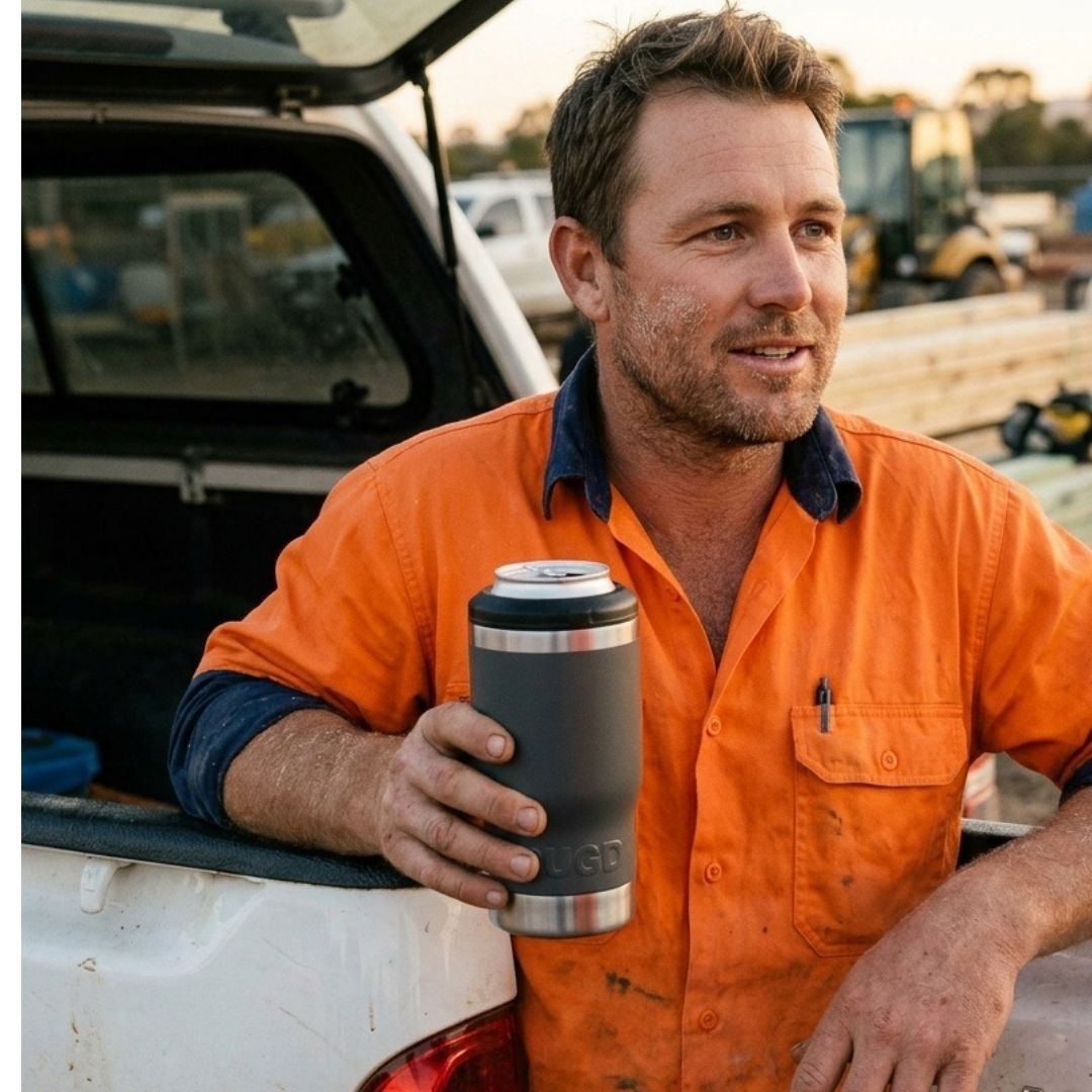 Australian tradie in hi-vis holding a black RUGD StubCup insulated stubby cooler with a beer can at knock-off on a worksite ute tray