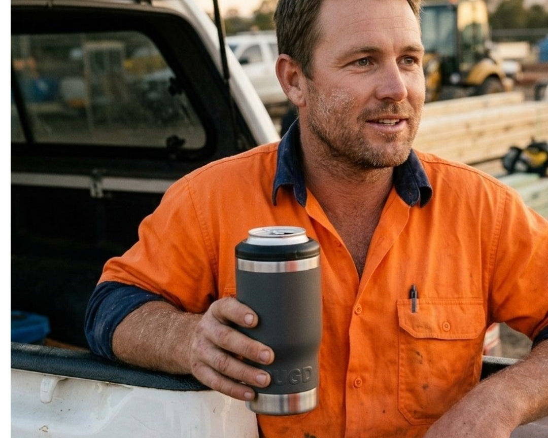 Australian tradie in hi-vis holding a black RUGD StubCup insulated stubby cooler with a beer can at knock-off on a worksite ute tray