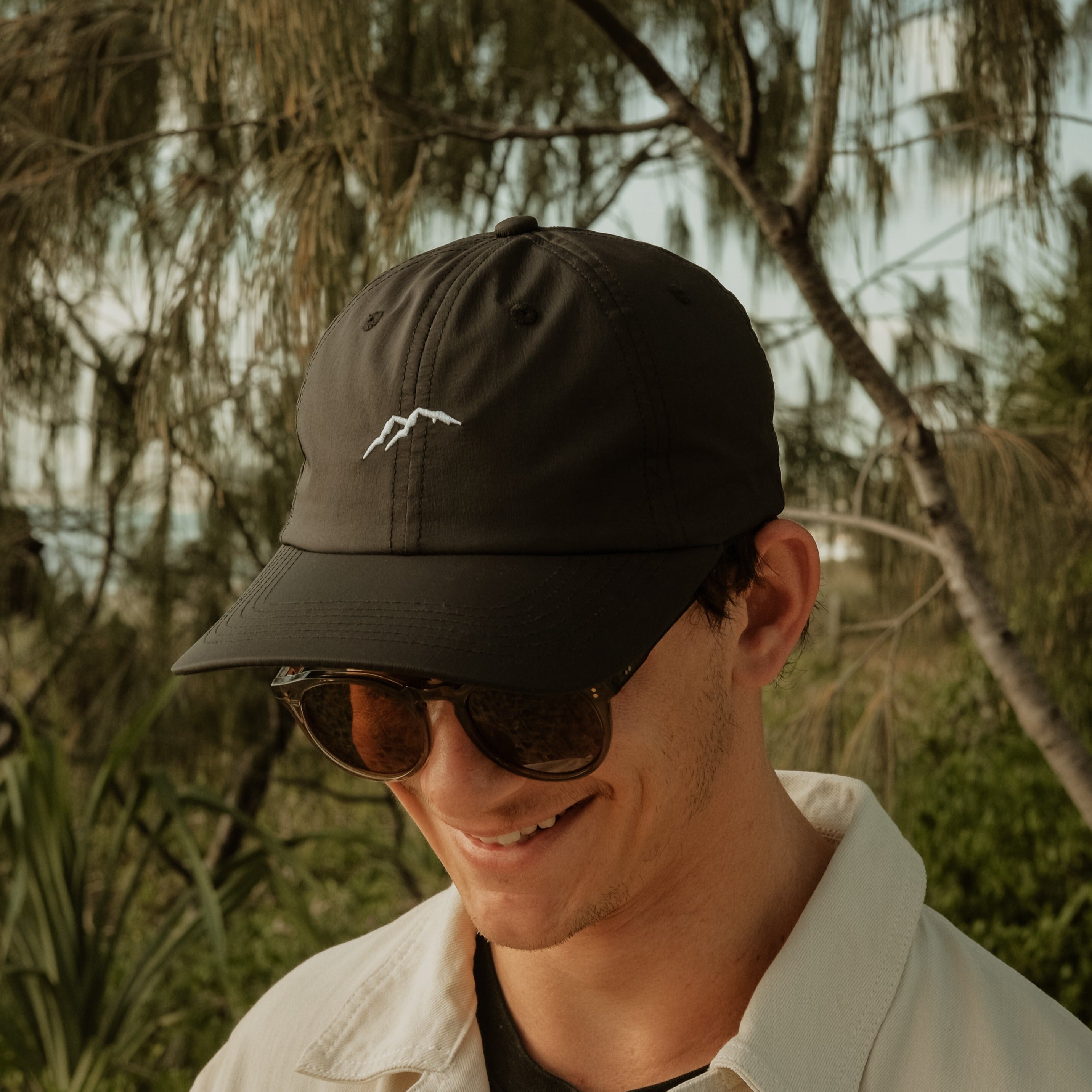 Get Rug'd Dad Cap Black worn by a man in front of palm trees