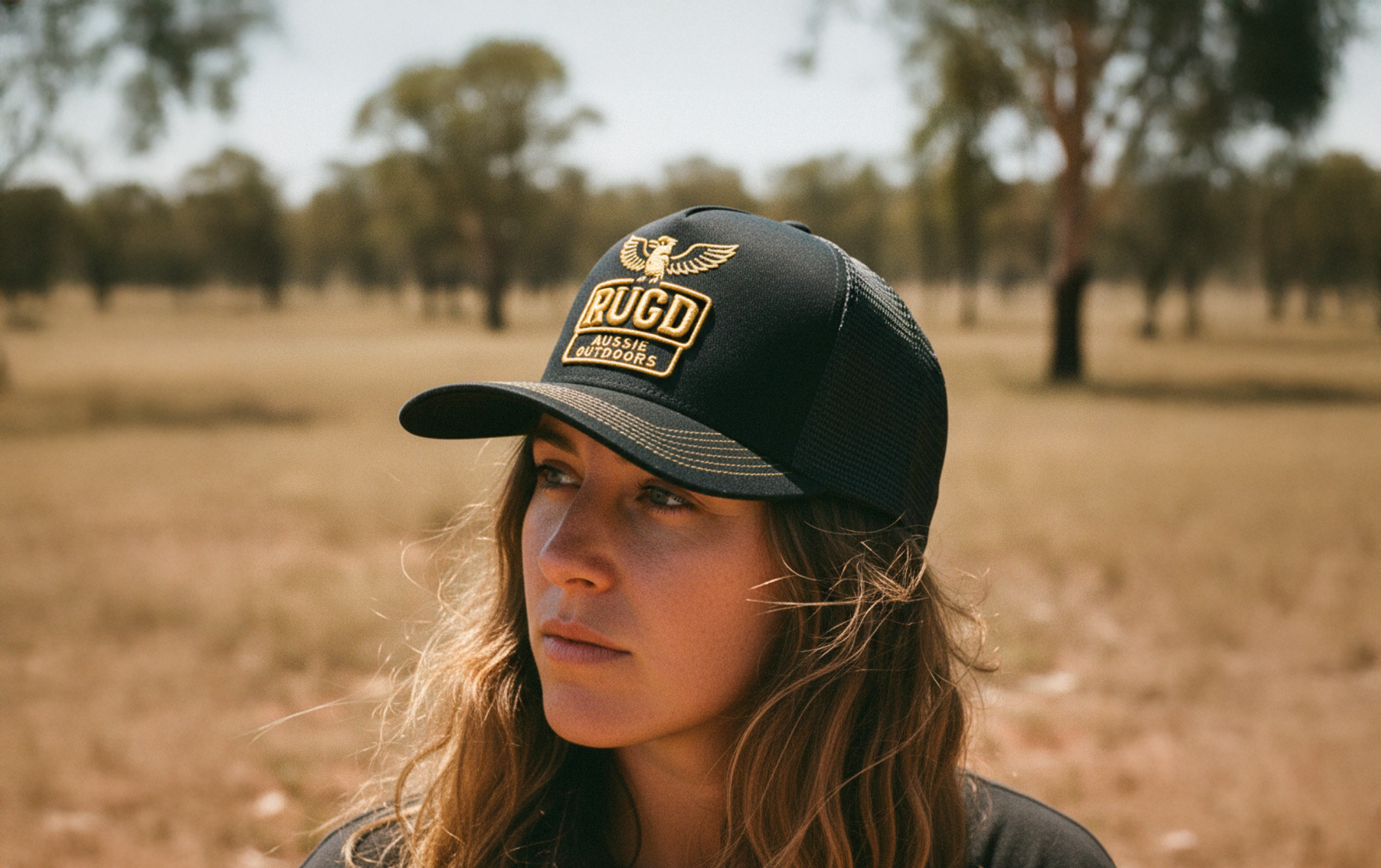 Person wearing a black cap with a logo in an outdoor setting