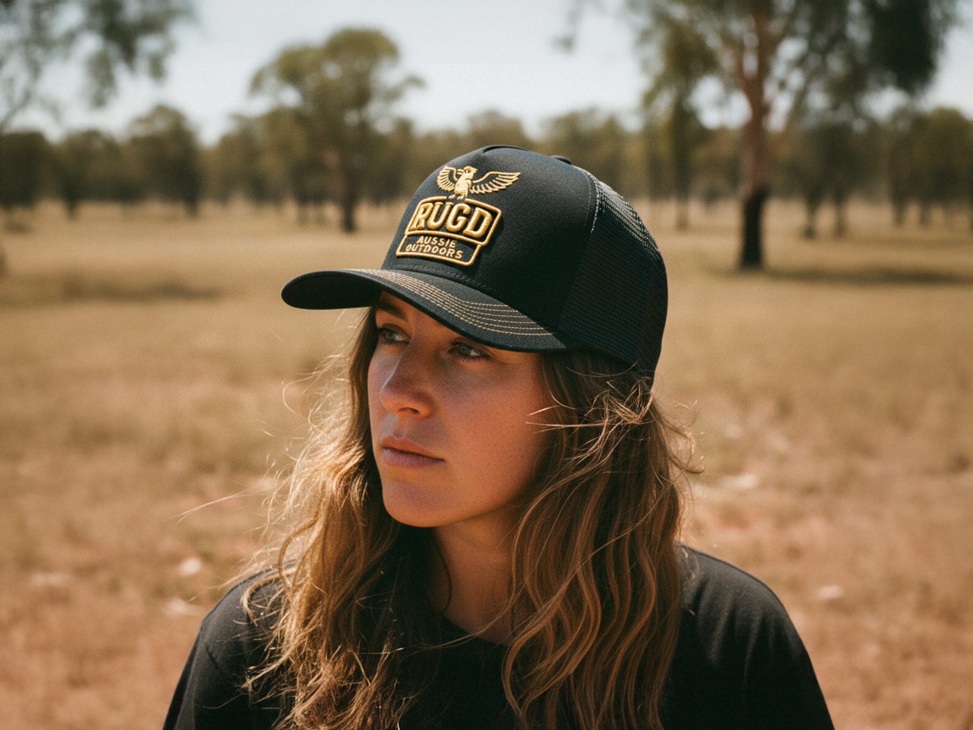 Person wearing a black cap with a logo in an outdoor setting