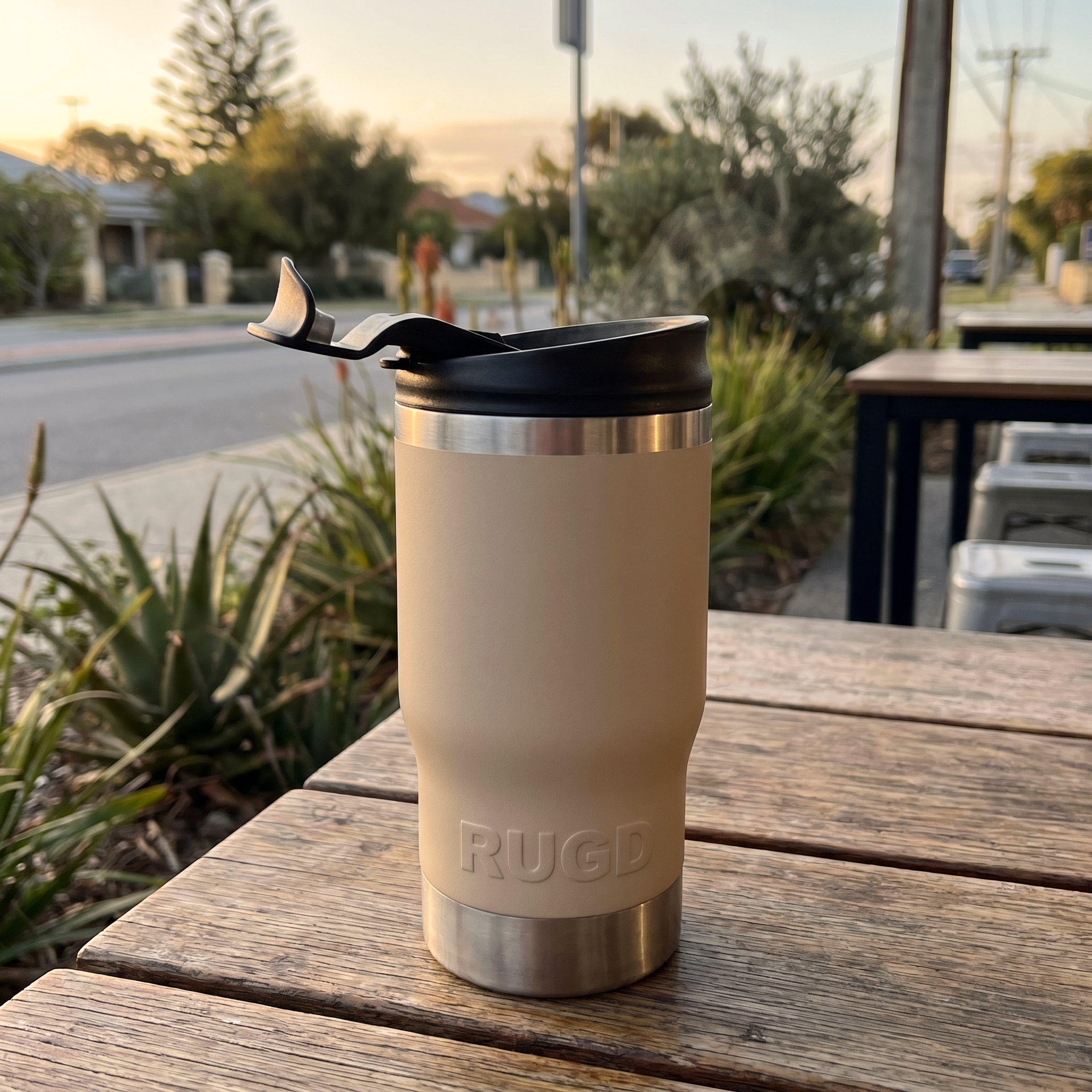 StubCup Beige stubby holder and coffee cup with a sleek design, placed on a wooden table outdoors
