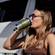 Woman drinking from a StubCup Green Stubby Cooler Coffee Cup by Get Rug'd outdoors in sunlight