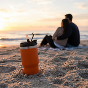StubCup orange can stubby holder cooler coffee cup on the beach during sunset